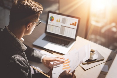 businessman going over financial charts on computer screen