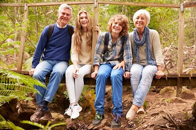 Grandparents and teens sit on bridge in forest